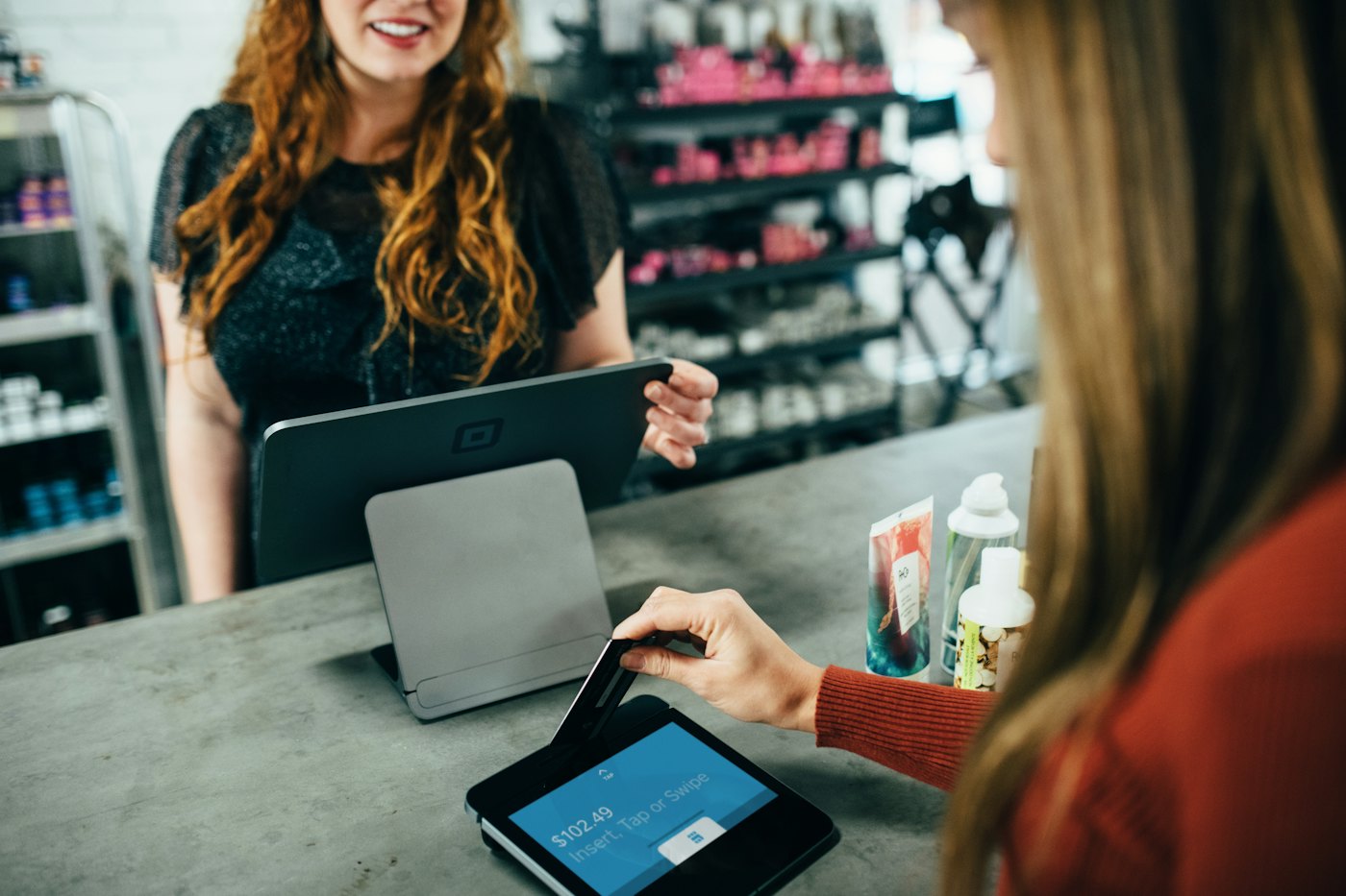 Dependienta cobrando a una clienta con una tablet en el mostrador